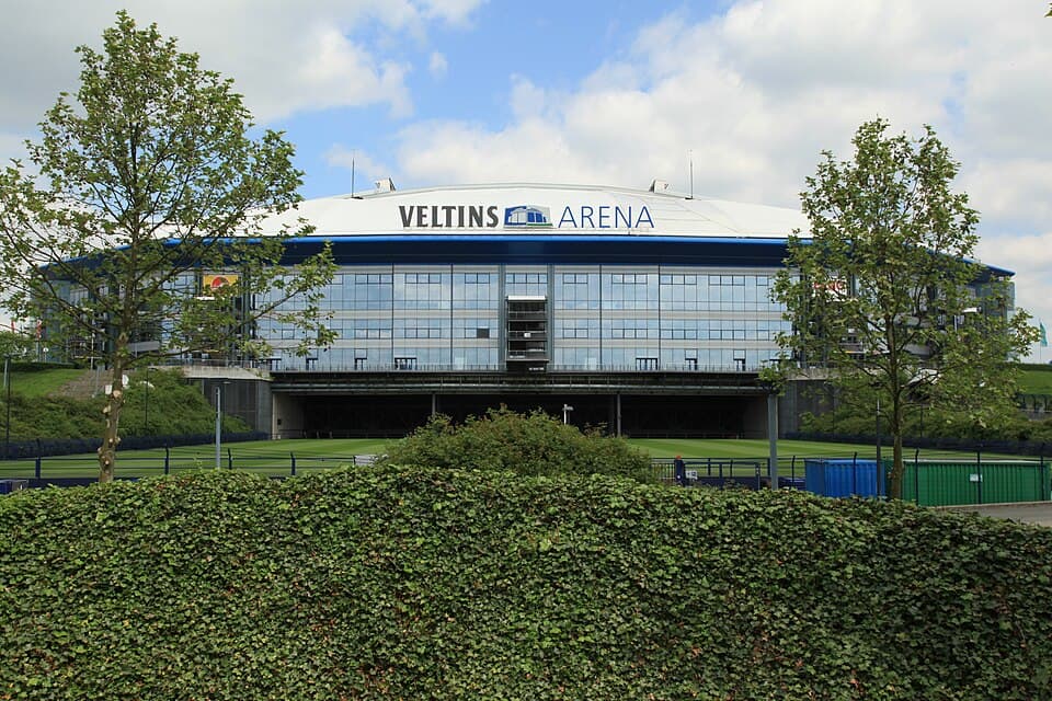 Blick auf ein leeres Fußballstadion mit grünem Rasen und leeren Rängen vor Spielbeginn