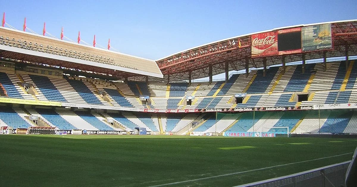General view of an empty football stadium with green pitch and stands before kickoff